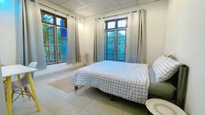a bedroom with a bed and a table and two windows at Silpasom ARTstay in Ban Takuk Nua