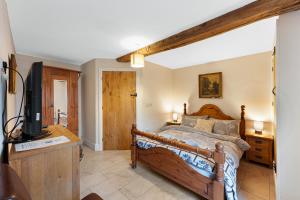 a bedroom with a wooden bed and a television at Host & Stay - The Barn - Upper Farm in Tideswell