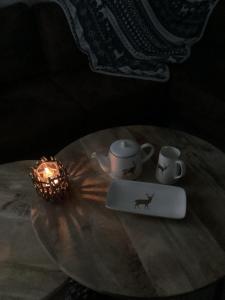 una mesa con una vela y dos tazas y un ordenador portátil en la maison de bievre, en Bièvre