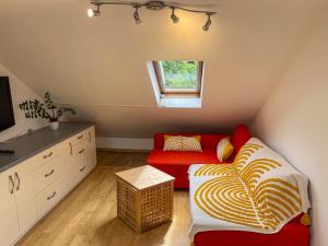 ロンドンにある1 Bed Attic Flat with Easy Reach to City Centreのリビングルーム(赤いソファ、窓付)