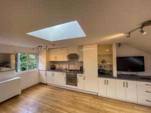 a large kitchen with white cabinets and a flat screen tv at 1 Bed Attic Flat with Easy Reach to City Centre in London