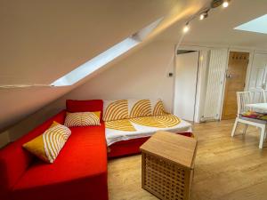 sala de estar con sofá rojo y cama en 1 Bed Attic Flat with Easy Reach to City Centre, en Londres