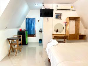 1 dormitorio con cama, mesa y espejo en Pijittra Resort en Uttaradit