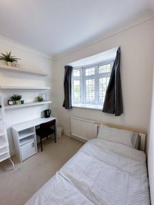 a bedroom with a bed and a desk and a window at Homestay - En-suites in New Malden