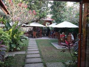 a patio with tables and chairs and umbrellas at Puri Batu Inn in Pemuteran