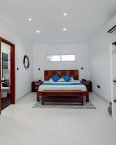 a white bedroom with a bed and a bathroom at Trio Villas Watamu in Watamu