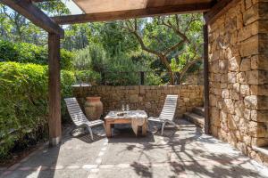 a patio with a table and two chairs and a stone wall at Vallegrande Nature Resort by Geocharme in Cefalù