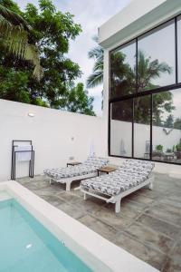 2 Betten auf einer Terrasse neben einem Pool in der Unterkunft Trio Villas Watamu in Watamu