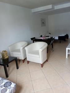 een woonkamer met 2 witte stoelen en een tafel bij Apartaments ENGAIT in Pas de la Casa