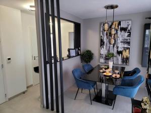 a dining room with a black table and blue chairs at Appartement neuf moderne + parking, Genève in Saint-Genis-Pouilly
