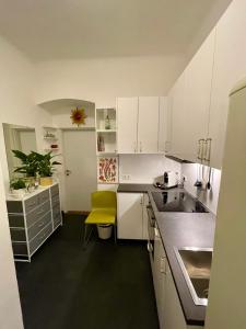 eine Küche mit weißen Schränken und einem gelben Stuhl in der Unterkunft Your home in Vienna Self Check In in Wien