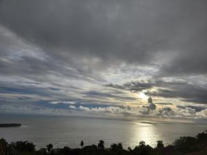 a cloudy sky over the ocean with the sun shining at Seascape Villa in Ānjarle