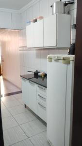 a kitchen with white cabinets and a black counter top at HOSTEL VENDA NOVA in Belo Horizonte