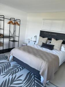 a bedroom with a large bed and a chair at TAKE TWO lovely beach apartment, Great Brak River in Groot Brak Rivier