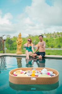 a man and a woman sitting in a swimming pool at The Pyramid Ubud River Villas in Gianyar