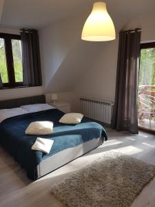 a bedroom with a bed with a blue blanket and pillows at Hacjenda in Boszkowo-Letnisko