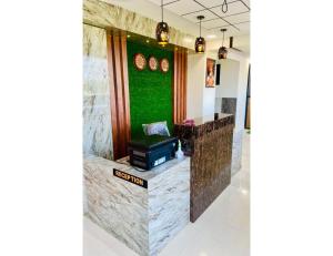 a reception desk in a lobby with a green wall at Hotel Paradise, Naroda in Ahmedabad