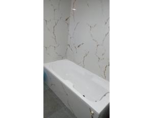 a bathroom with a white tub and a white wall at Hotel Paradise, Naroda in Ahmedabad