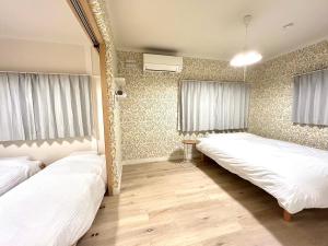 two beds in a room with curtains and wooden floors at わらしべハウス in Furano