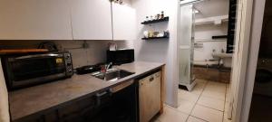 een keuken met een wastafel en een magnetron bij Cheap and very central basement apartment - Vindegade 53F in Odense