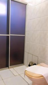 a bathroom with a toilet and a glass shower door at HOTEL VILLA QUATI CENTRO in Foz do Iguaçu