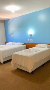 two beds in a room with a blue wall at HOTEL VILLA QUATI CENTRO in Foz do Iguaçu