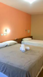 two beds in a room with orange walls at HOTEL VILLA QUATI CENTRO in Foz do Iguaçu