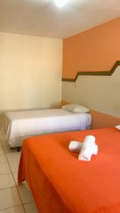 two beds in a room with orange and white at HOTEL VILLA QUATI CENTRO in Foz do Iguaçu
