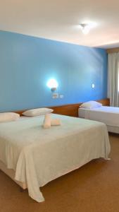 a bedroom with two beds and a blue wall at HOTEL VILLA QUATI CENTRO in Foz do Iguaçu