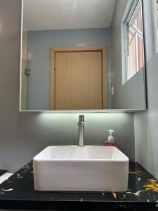 een badkamer met een witte wastafel en een spiegel bij Serene Nook, Hyde Residences -Two Beds in Cebu City