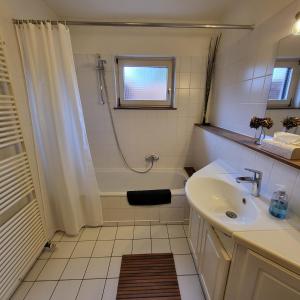 La salle de bains blanche est pourvue d'un lavabo et d'une douche. dans l'établissement Ferienwohnung Worpswede-in-Sicht, à Lilienthal