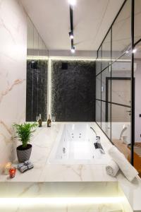 un bagno con grande vasca bianca con una pianta in vaso di LEOGRAND Apartments on Shevchenka 38 a Lviv