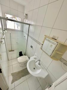 a white bathroom with a toilet and a sink at Hostel Encanto de Mongaguá in Mongaguá