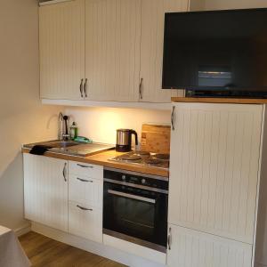 uma cozinha com armários brancos, um fogão e um micro-ondas em Ferienwohnung Worpswede-in-Sicht em Lilienthal