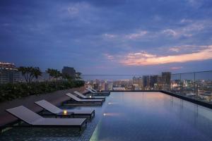 a swimming pool with lounge chairs on top of a building at Courtyard by Marriott Phnom Penh in Phnom Penh