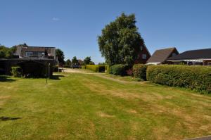a yard with green grass and a house at Haus Dorfschmiede, Wohnung Anker in Alkersum
