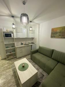 uma sala de estar com um sofá verde e uma mesa em Apartman Dunja em Divčibare