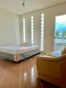 a bedroom with two beds and two chairs and a window at Hostel Encanto de Mongaguá in Mongaguá