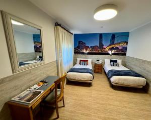 a hotel room with two beds and a desk and a table at Hotel Artetxe in Bilbao