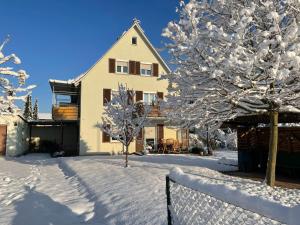 dom z drzewami pokrytymi śniegiem i ogrodzeniem w obiekcie BergBlick am See w mieście Friedrichshafen