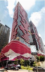een hoog rood gebouw met auto's geparkeerd voor het bij FHS Homestay @ Arte Plus Jalan Ampang T3-33A-07 in Kuala Lumpur