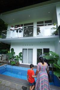 een vrouw en een kind die voor een huis staan bij Ultra Modern Glass house with large Swimming pool and garden in Kottayam