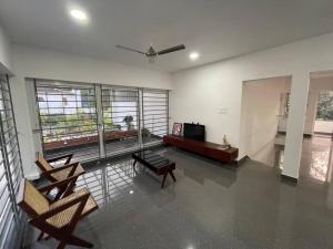 uma sala de estar com cadeiras, um sofá e uma televisão em Ultra Modern Glass house with large Swimming pool and garden em Kottayam