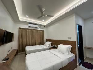 Habitación de hotel con 2 camas y TV de pantalla plana. en SRI KRISHNA RESIDENCY en Tiruchchirāppalli