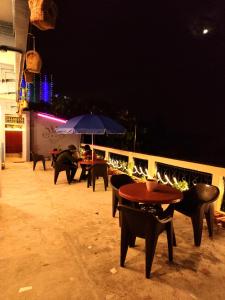 grupa stołów i krzeseł z parasolami w nocy w obiekcie Hidden Monkey Hostels w mieście Dardżyling