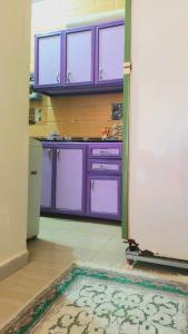 a kitchen with purple cabinets and a rug on the floor at Mooody nobin haws in Abu Simbel
