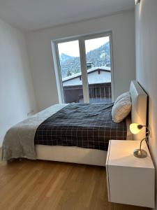 ein Schlafzimmer mit einem Bett und einem großen Fenster in der Unterkunft Geräumiges modernes Apartment 1-6 Personen in Imst