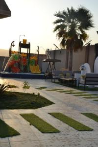 a patio with benches and a table and a palm tree at شالية ألأمراء 