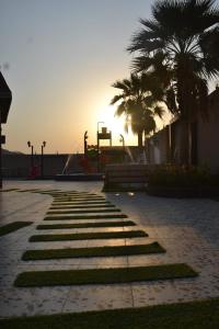 a pathway with palm trees and a playground with the sunset at شالية ألأمراء 