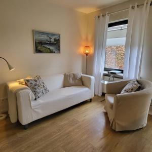 uma sala de estar com um sofá branco e uma cadeira em Ferienwohnung Worpswede-in-Sicht em Lilienthal
